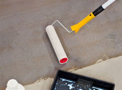 Illustratie van het aanbrengen van primer op een betonnen vloer met een roller, waarbij de randen eerst met een kwast worden gedaan.