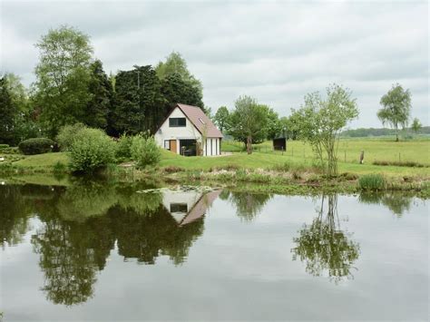 Een idyllisch vakantiehuisje aan een rustig meer met weerspiegeling in het water.