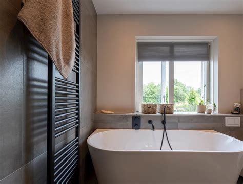 Zwart ligbad en witte balken voor contrast in een moderne badkamer