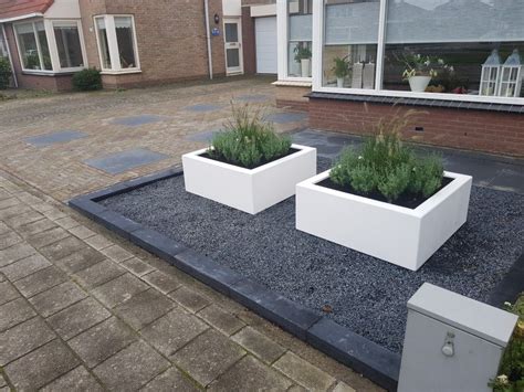 grote voortuin met antraciete tegels en plantenbakken