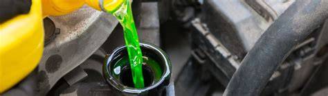 Foto van een plas koelvloeistof onder een auto (groen/oranje kleur)