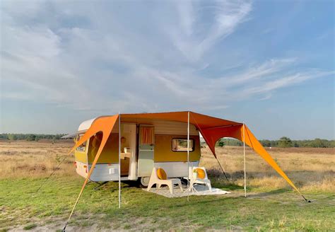 Illustratie van een moderne caravan met een openstaande luifel en een koelkast.