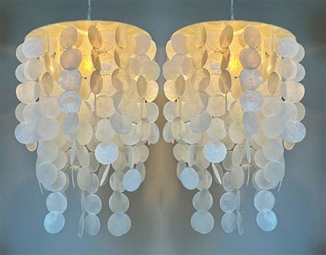 Collage van diverse Capiz schelpen lampen in verschillende stijlen en maten, waaronder hanglampen, plafonnières en kroonluchters.