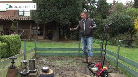 Beeld van een tuinfrees die de grond bewerkt, waarbij de messen de grond losmaken en wortels verwijderen.