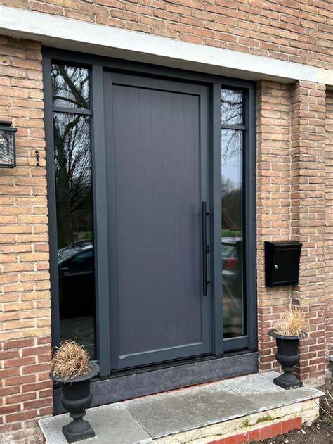 Donkergrijze glaspanelen in een moderne voordeur, met zijlichten