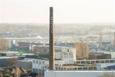 Visualisatie van de 55 meter hoge Coberco schoorsteen in Deventer, met nadruk op de gele bakstenen en metalen ringen.