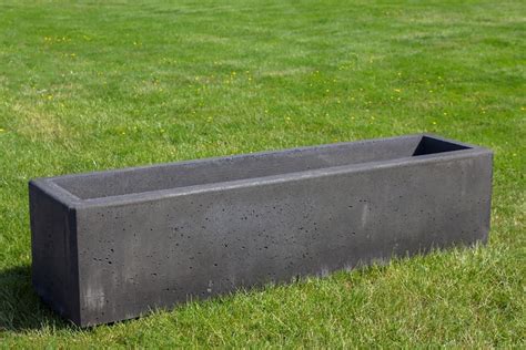 Verschillende maten en vormen van betonnen bloembakken in een tuinsetting