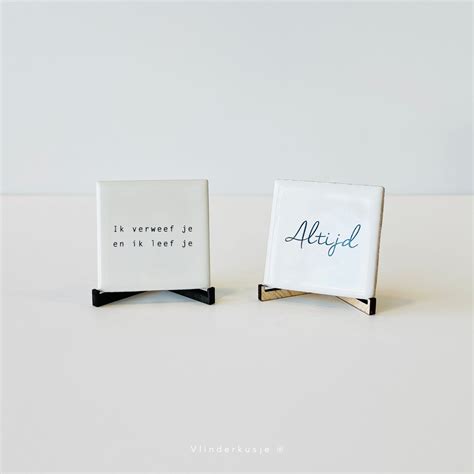 Een voorbeeld van vier gepersonaliseerde tegeltjes in een houten lijst.