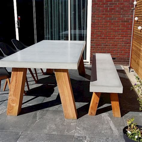 Foto van een duurzame betonnen tuintafel met twee betonnen tuinbanken in een moderne tuinomgeving