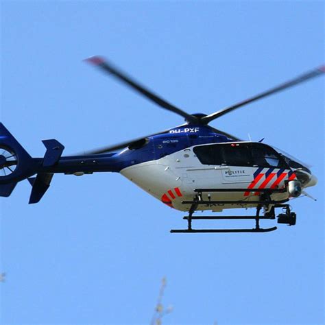 Illustratie van een politiehelikopter die boven een woonwijk vliegt tijdens een opsporingsactie