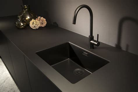 Een stijlvolle keuken met een mat zwarte spoelbak, een zwarte Quooker kraan en een bijpassend werkblad.