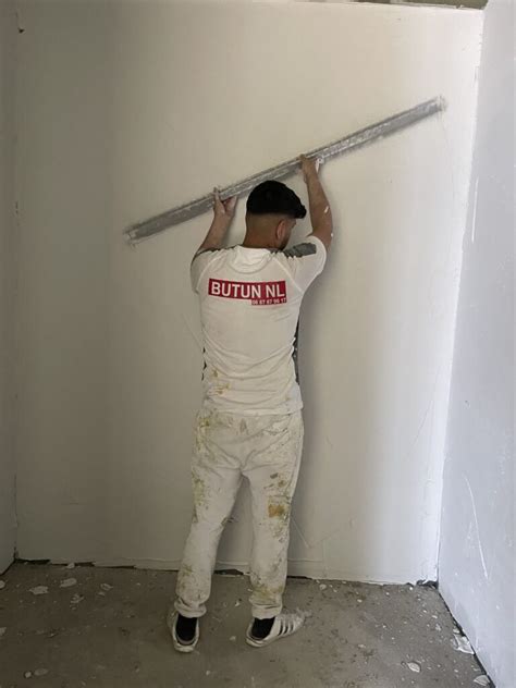Professioneel stucadoor aan het werk aan een muur in een moderne woonkamer