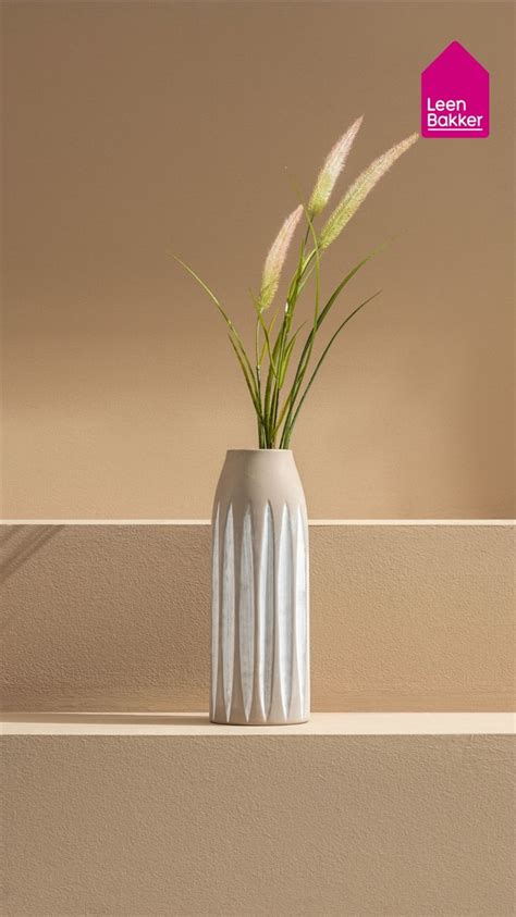 Stijlvolle opstelling van witte en beige vazen in verschillende vormen en maten, met pastelkleurige bloemen.